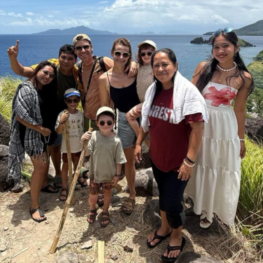ravelers and locals hiking together on Sambawan Island, Philippines, with scenic ocean view in background.